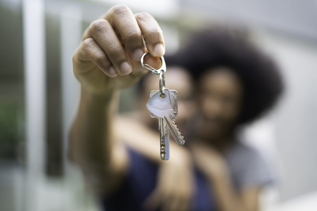 young couple in front of a house, holding keys of their new home